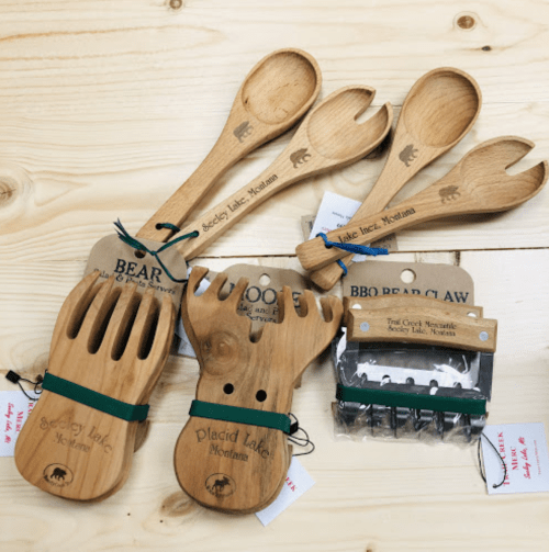 A collection of wooden kitchen utensils, including bear-themed serving forks and spoons, on a wooden surface.