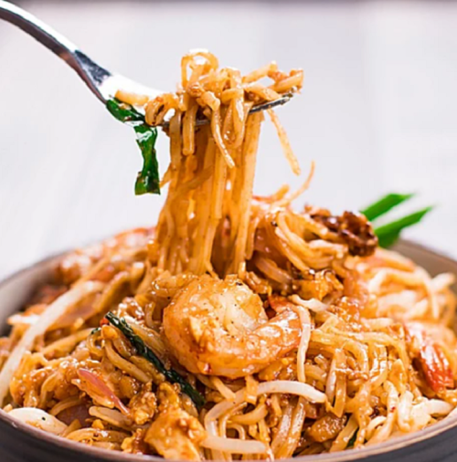 A fork lifting a serving of shrimp stir-fried noodles with vegetables in a bowl.