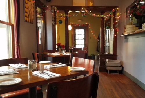 Cozy restaurant interior with wooden tables, festive decorations, and warm lighting.