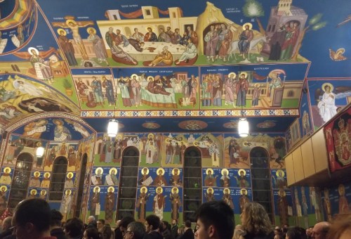 Interior of a church with vibrant frescoes on the ceiling and walls, depicting religious figures and scenes.