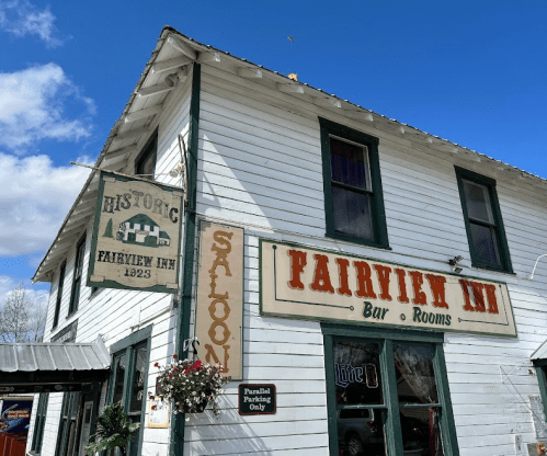 Historic Fairview Inn with a saloon sign, featuring a white wooden exterior and blue sky in the background.
