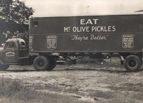 A vintage truck advertising "Mt. Olive Pickles" with the slogan "They're Better" on its side.