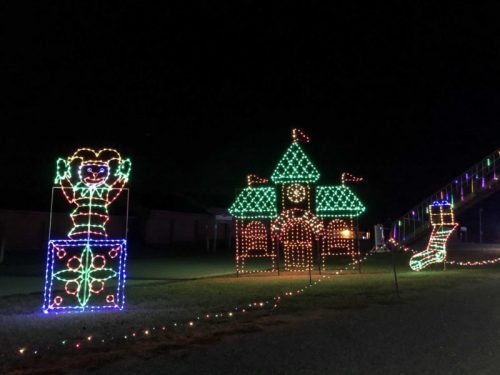 Colorful holiday lights display featuring a clown, a castle, and a Christmas stocking against a dark night sky.