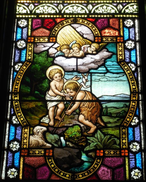 Stained glass window depicting a biblical scene with children, nature, and angels above, vibrant colors and intricate details.