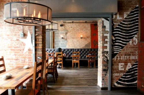 Cozy restaurant interior featuring brick walls, wooden tables, and a stylish chandelier.