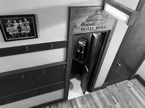 A vintage phone booth entrance at Hotel Wolf, with a framed photo of women on the wall nearby.