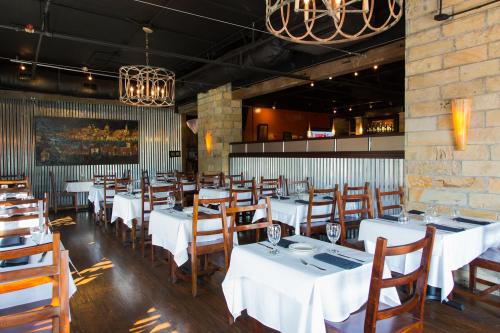 Interior of a restaurant featuring wooden chairs, white tablecloths, and warm lighting with a rustic decor.