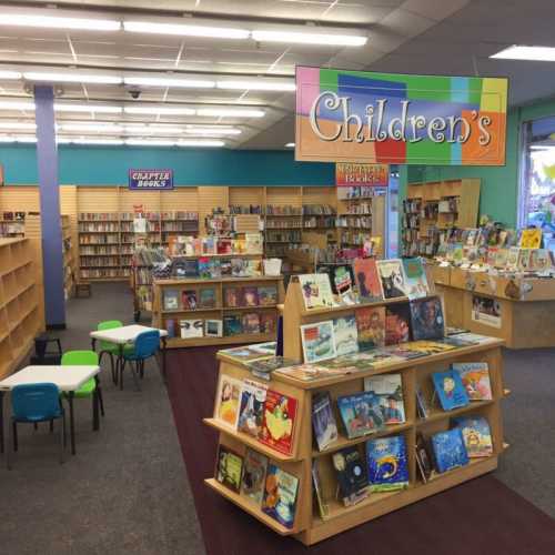 A colorful children's section in a library, featuring bookshelves, tables, and chairs for young readers.