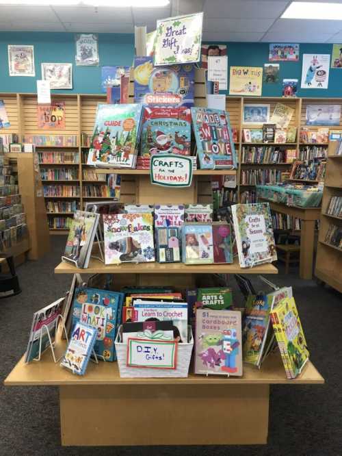 A colorful display of children's craft books in a library, featuring holiday themes and DIY projects.