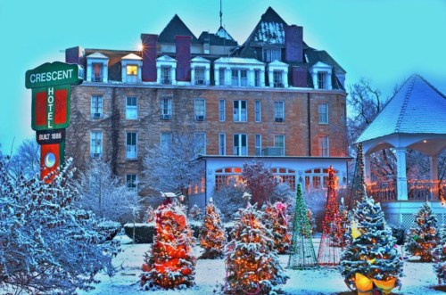 Historic Crescent Hotel surrounded by snow-covered trees and festive lights, creating a winter wonderland scene.