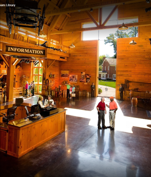 A bright wooden interior of a visitor center with people at an information desk and others exploring the space.