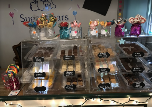 A display of colorful sweets and desserts in jars and trays, featuring various candies and chocolate treats.