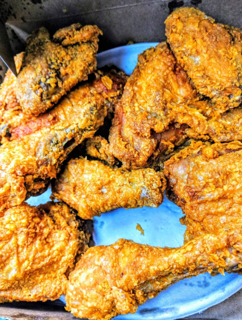 A close-up of crispy, golden-brown fried chicken pieces on a blue plate.