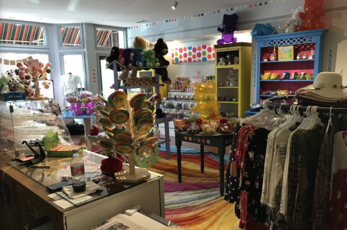 A colorful shop interior filled with candy, toys, and clothing, featuring bright decor and a vibrant rug.