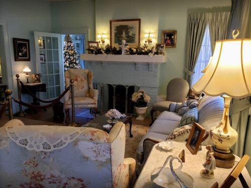 Cozy living room decorated for the holidays, featuring a Christmas tree, elegant furniture, and soft lighting.
