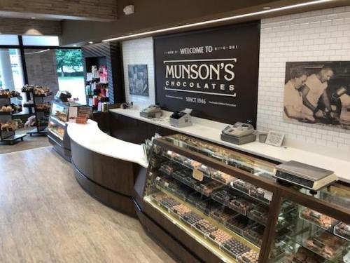 Interior of Munson's Chocolates store featuring display cases, a counter, and vintage photos on the wall.