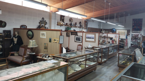 A spacious antique shop featuring display cases, vintage furniture, and various collectibles on the walls.