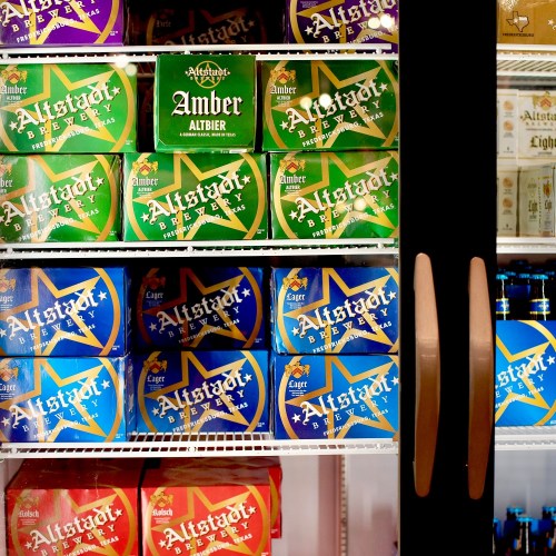 A refrigerator stocked with various brands of Alstadt beer in colorful packaging.