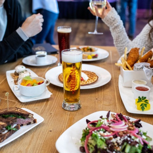 A table spread with various dishes, including salad, fries, and a beer, set in a casual dining environment.