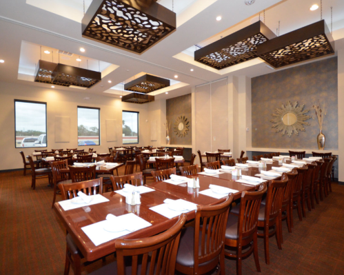 A spacious restaurant interior with wooden tables, chairs, and decorative ceiling lights.