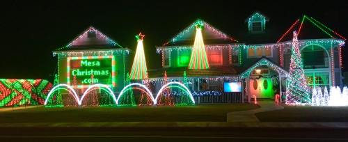 A brightly lit house decorated for Christmas with colorful lights, trees, and festive displays.