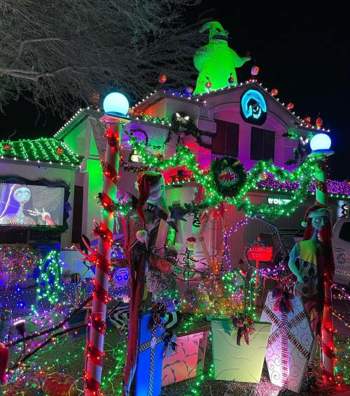 A festive house decorated with colorful lights, featuring characters from "The Nightmare Before Christmas" and holiday decorations.