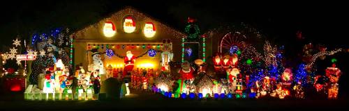 A festive house decorated with colorful Christmas lights, snowmen, and various holiday figures.