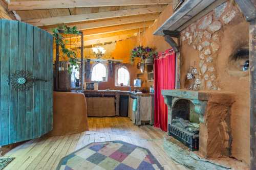 Cozy interior of a rustic home with wooden beams, a stone fireplace, and colorful decor.