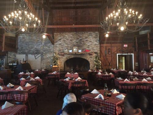 Cozy restaurant interior with checkered tablecloths, a large fireplace, and festive decorations.