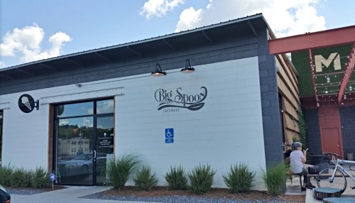 Exterior of Big Spoon restaurant with a large sign, featuring a person sitting outside and decorative plants.