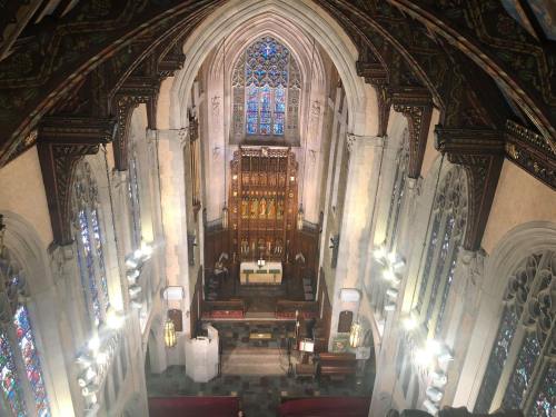 Aerial view of a grand church interior featuring stained glass windows and ornate wooden altar.