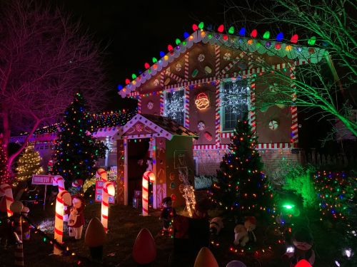 A festive house decorated with colorful lights, candy canes, and Christmas trees, creating a cheerful holiday scene.