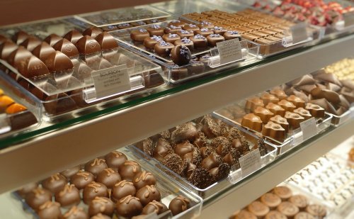 A display case filled with various chocolates, including truffles and pralines, arranged neatly in clear containers.