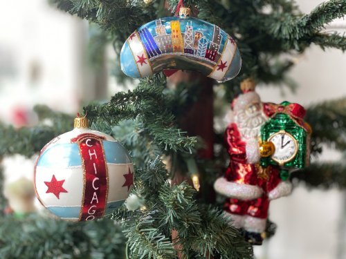 Colorful Christmas ornaments, including a Chicago-themed ball and a Santa figure, hang on a decorated tree.