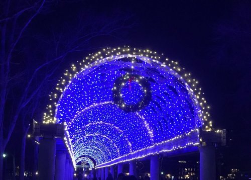 A beautifully lit archway adorned with blue lights and a wreath, creating a festive atmosphere at night.