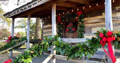 A rustic wooden cabin decorated with festive wreaths and bows for the holiday season.