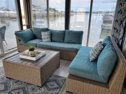 Cozy indoor seating area with a blue couch and coffee table, overlooking a marina through large glass windows.