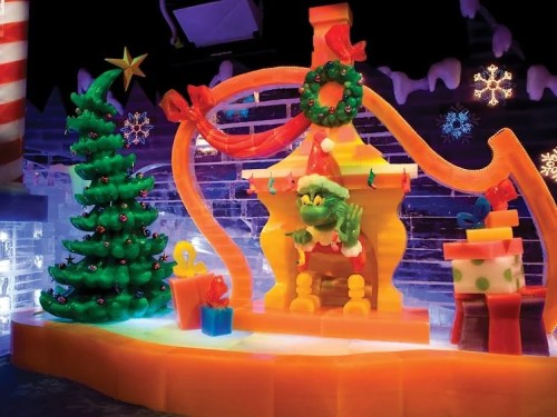 Colorful ice sculpture featuring the Grinch in a Santa hat, surrounded by a Christmas tree and festive decorations.