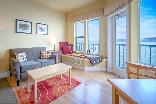 Cozy living area with a sofa, coffee table, and a window seat overlooking a scenic view of the water.