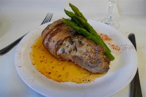 A plate with a seasoned meat dish, garnished with asparagus, served in a flavorful sauce.