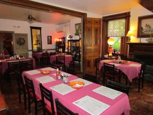 Cozy restaurant interior with tables set for dining, warm lighting, and decorative elements creating an inviting atmosphere.