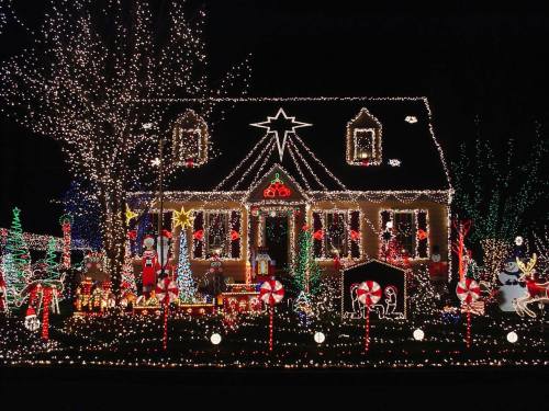 A beautifully decorated house with colorful Christmas lights, featuring festive figures and holiday decorations.