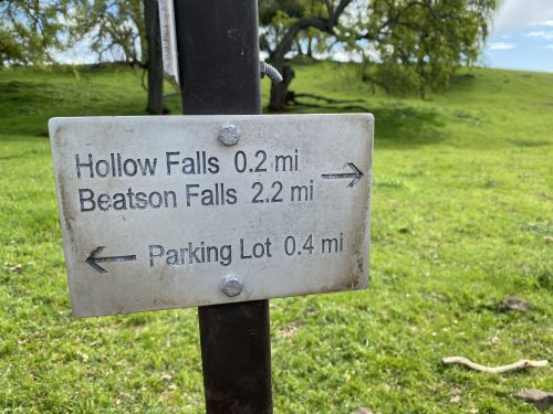 Signpost indicating directions and distances to Hollow Falls (0.2 mi), Beatson Falls (2.2 mi), and Parking Lot (0.4 mi).