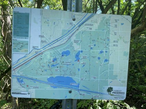 Map of a forest preserve area, showing trails, lakes, and surrounding roads in a green, wooded environment.