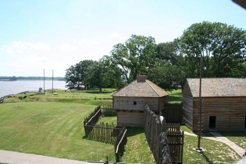 Historic wooden structures surrounded by greenery near a river, with a clear blue sky above.