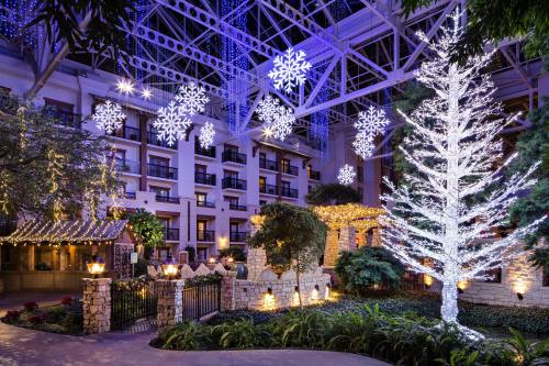 A beautifully lit indoor garden with a large white tree and snowflake decorations, creating a festive atmosphere.