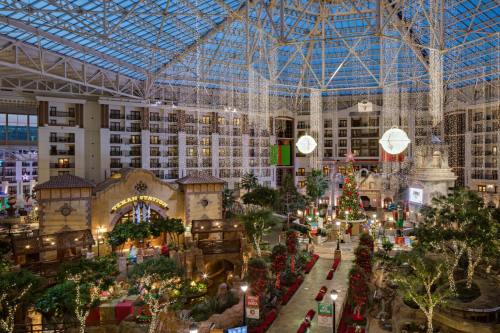 A festive indoor atrium decorated with holiday lights, a large Christmas tree, and lush greenery.