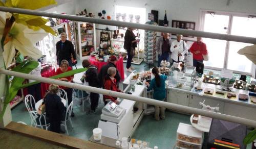 A busy shop interior with customers browsing and staff assisting, surrounded by colorful displays and products.