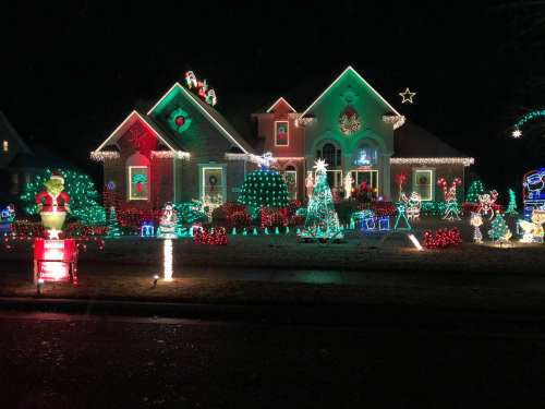 A brightly lit house decorated with colorful Christmas lights, featuring trees, Santa, and festive decorations.