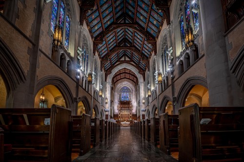 Interior of a grand church featuring stained glass windows, wooden pews, and a high, ornate ceiling.